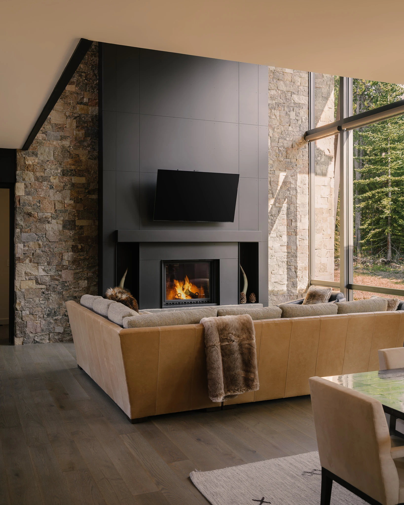 Great room fireplace and leather sectional with forest views — interior design photography Big Sky Montana, Speedwell Cabin